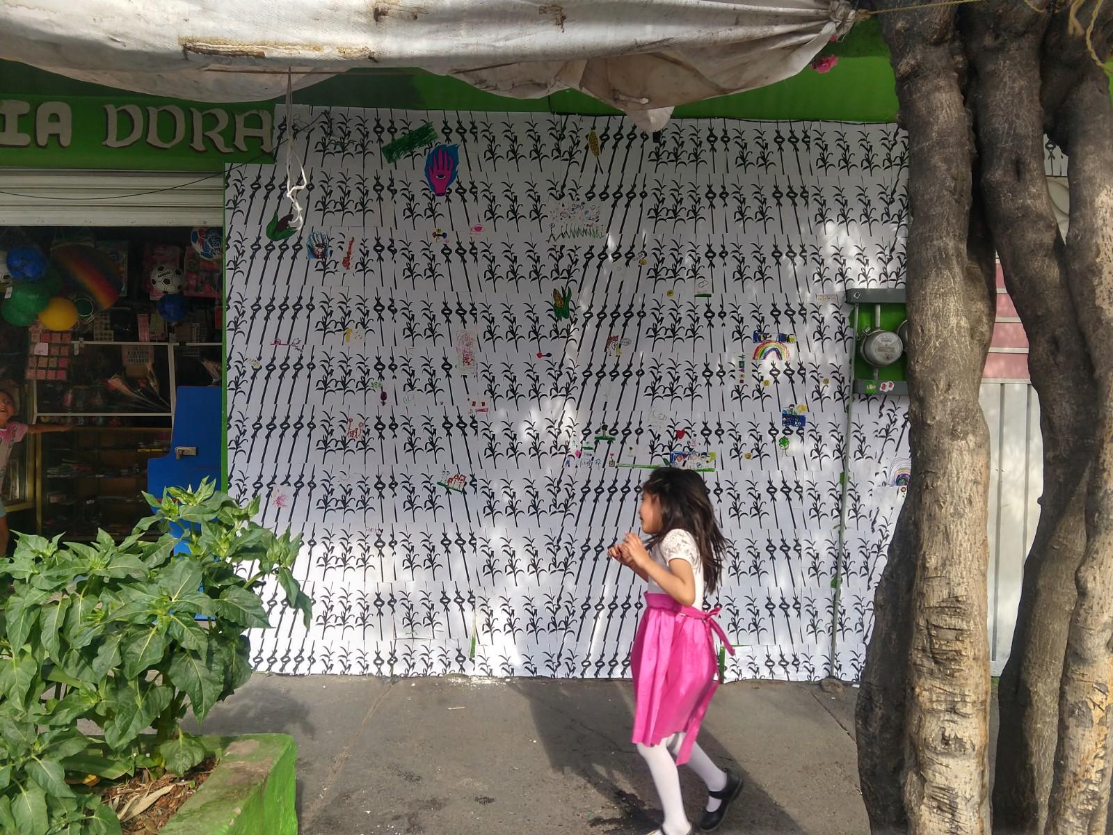 Fachada de una papelería de barrio con gráfica impresa pegada en el muro